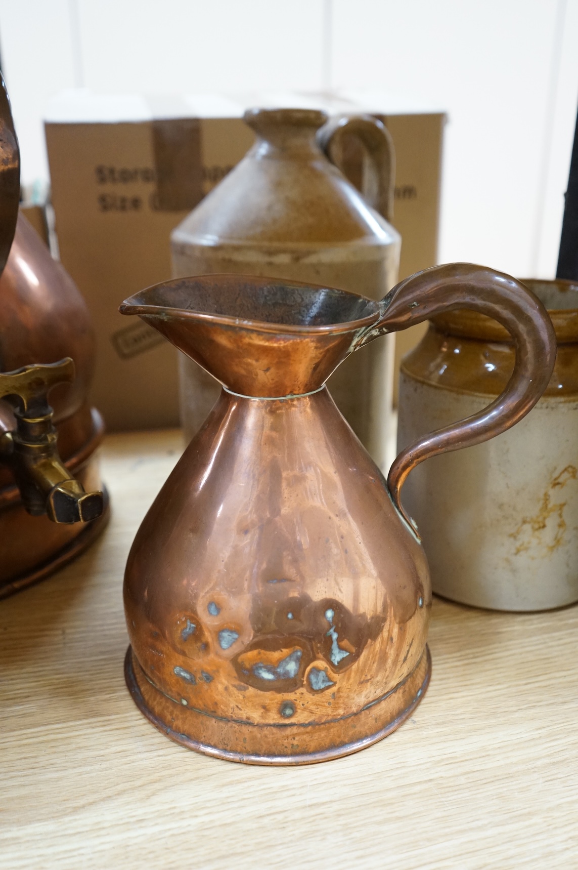 Three graduated copper haystack measures, H 39cm x W 40cm (inc spout), H 35cm x 25cm and H25cm x 18cm, Three stoneware jars H 32cm x W 20cm (two jars), H 20cm x W 16cm (1 jar)